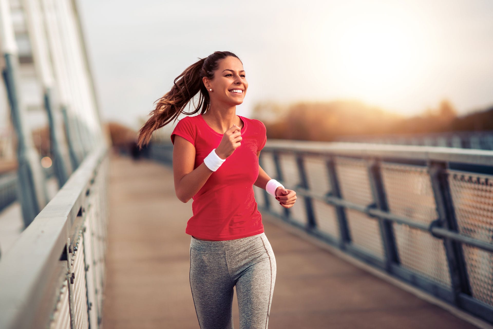 woman-running-outdoors-across-a-bridge-after-successful-coolsculpting-treatment