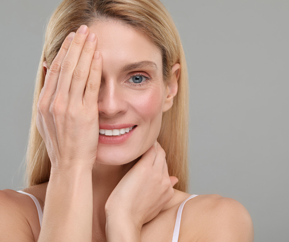 Smiling-middle-aged-woman-touching-smooth-skin-near-eyes