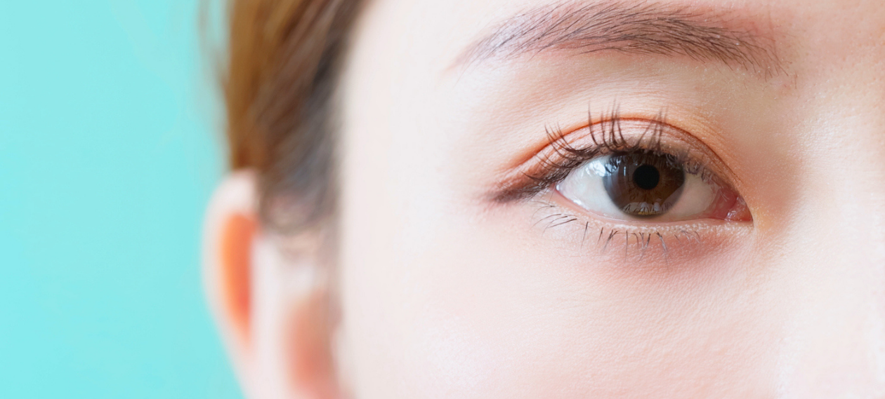 close-up of a woman's eye and brow against a pale blue background