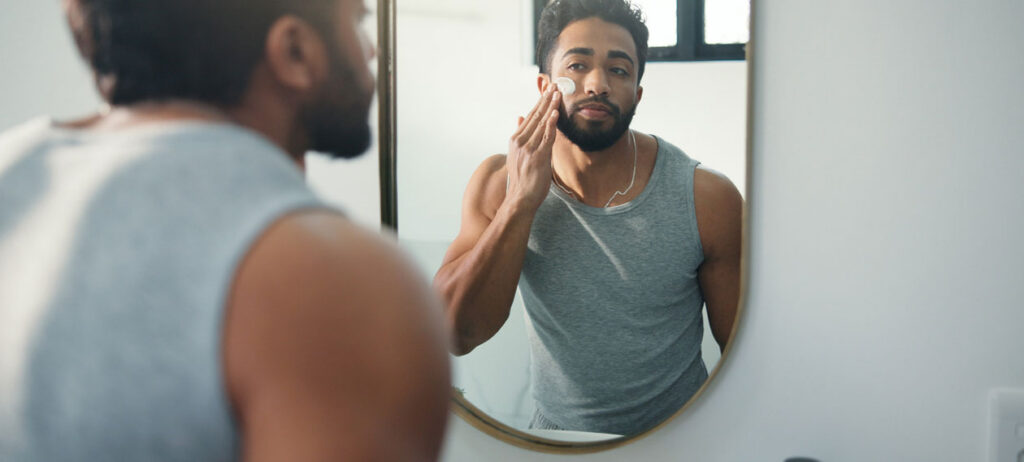 man-checking-his-skin-in-a-bathroom-mirror