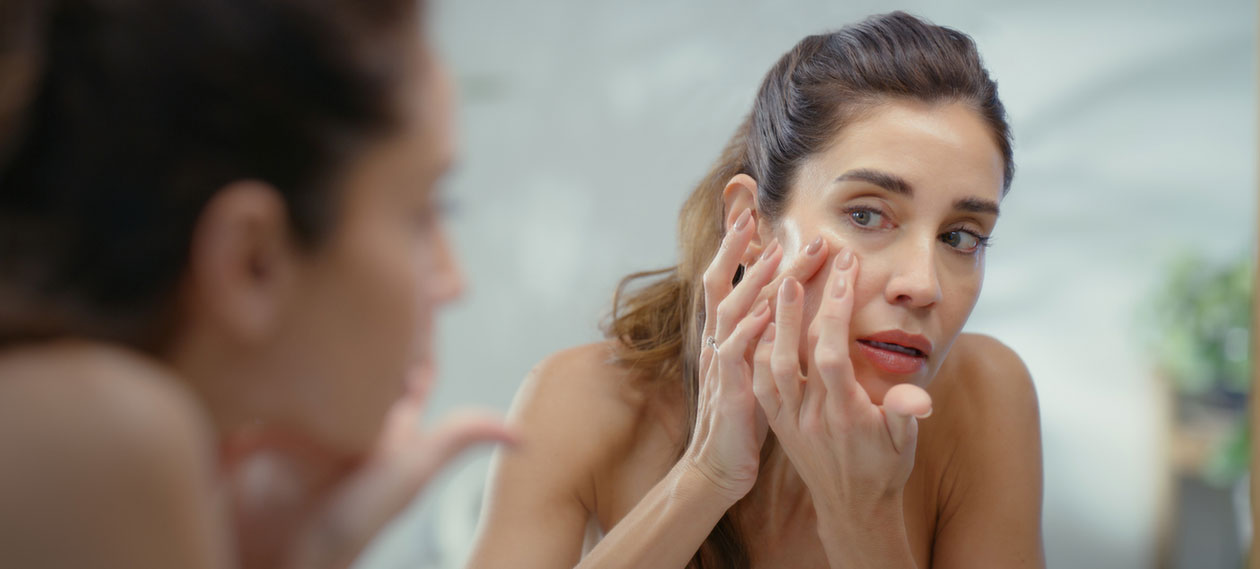woman-washing-her-face-at-a-bathroom-mirror