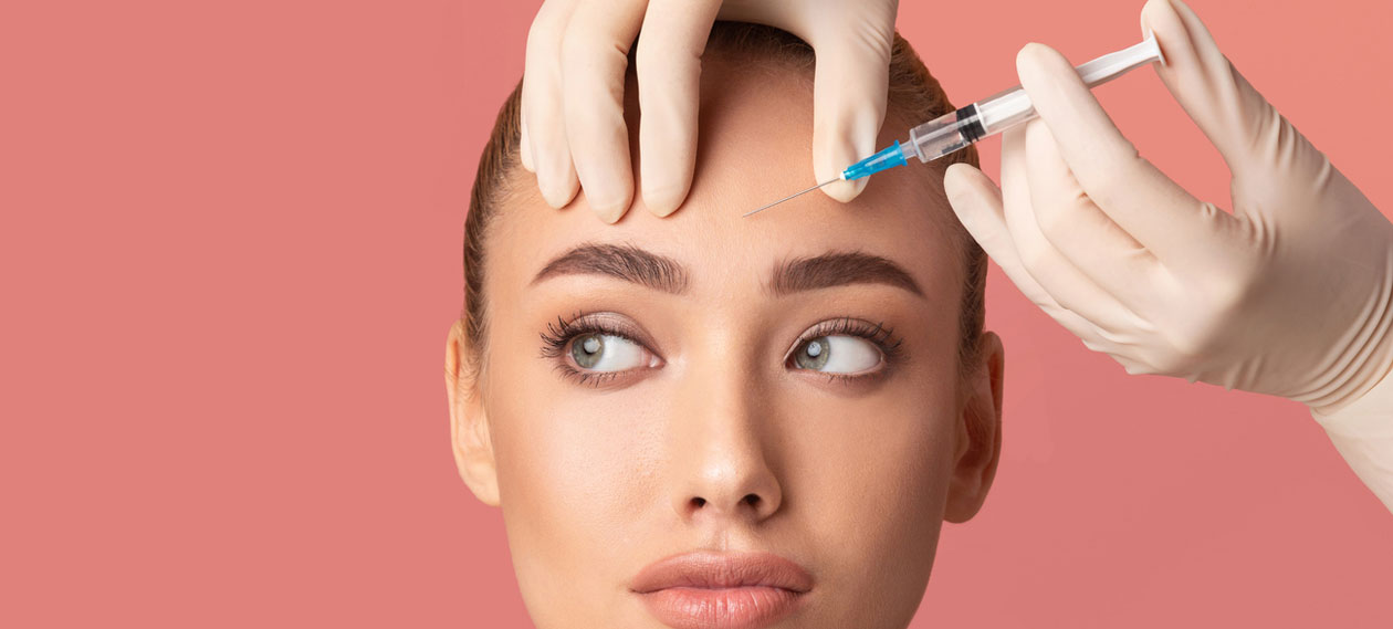 young-woman-receiving-injection-in-forehead-on-pink-background